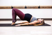 Bridge Yoga Pose wearing black support band and purple yoga leggings