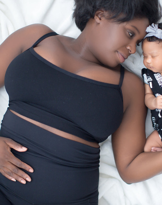 black mother lying on bed with infant
