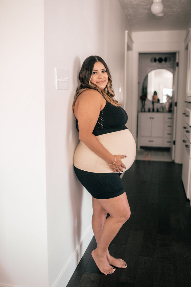 pregnant woman standing in hallway in black yoga shorts
