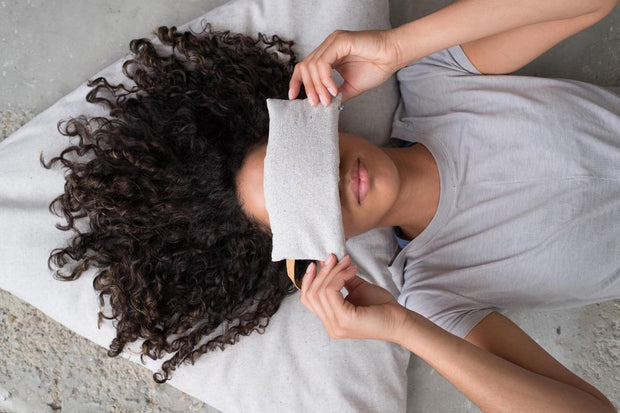 Woman lying down with eye pillow over eyes